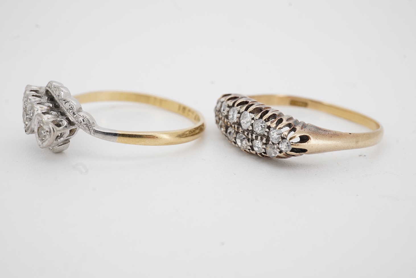A mid 20th century 18ct, plat. and three stone diamond chip crossover ring, each stone in a heart shaped setting, size Q, together with an 18ct and fourteen stone diamond set two row ring, size P/Q, gross weight 6 grams.